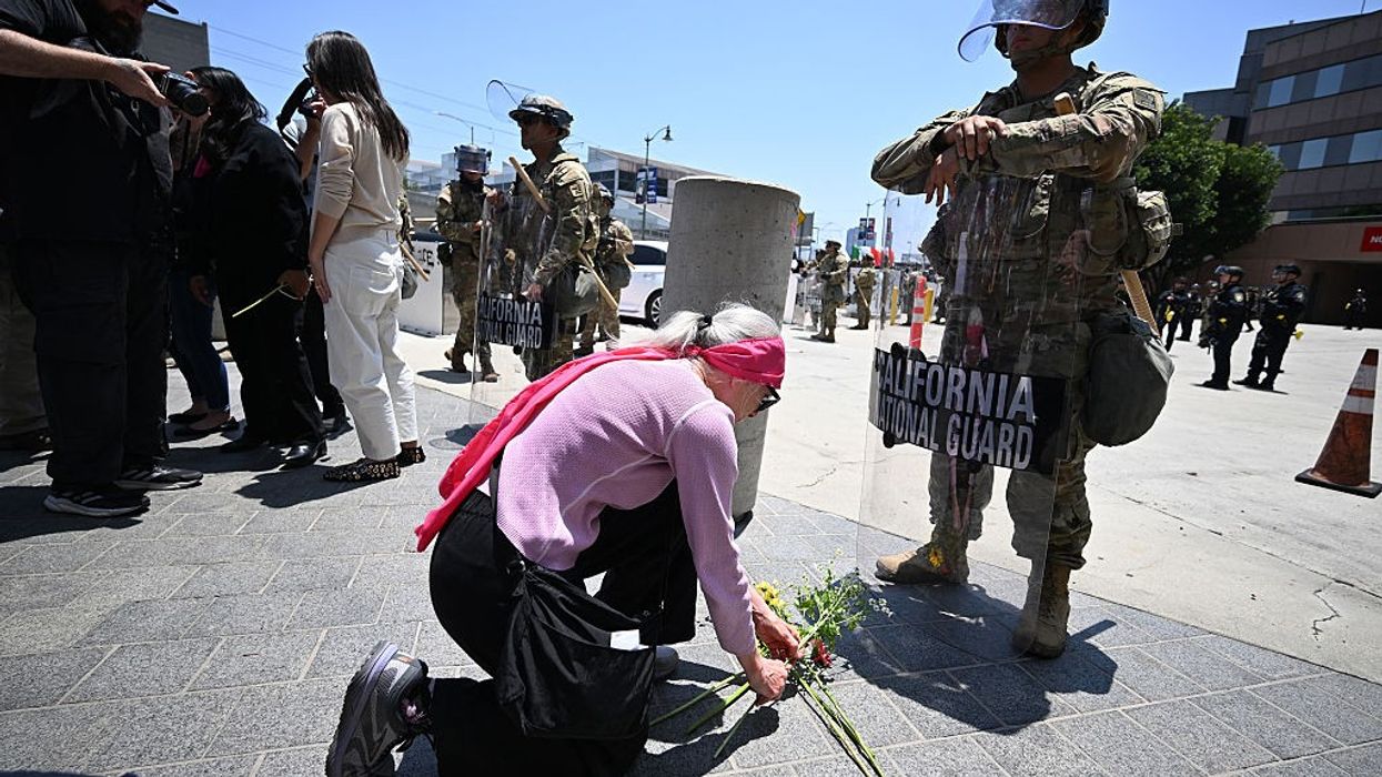 A protester places flowers at the feet of a National Guard member in LA.