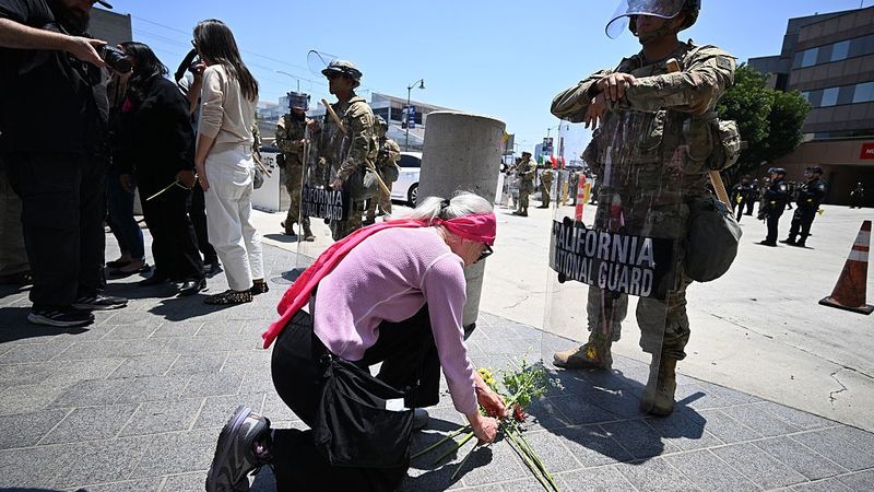 A protester places flowers at the feet of a National Guard member in LA.