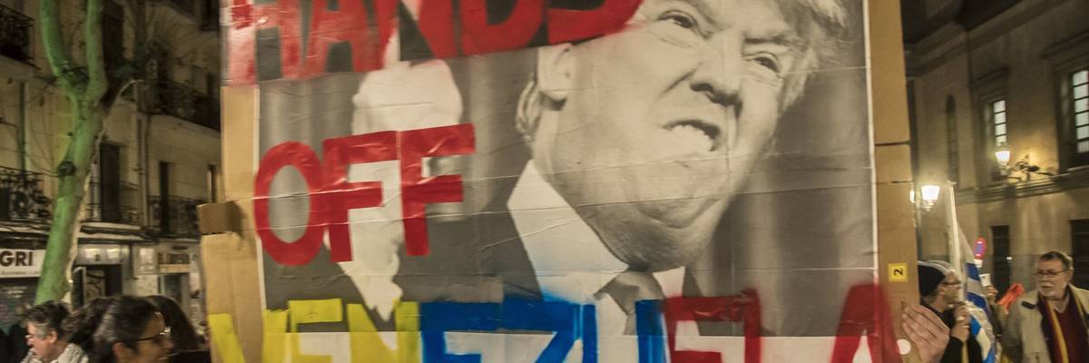 A protester seen holding a placard saying, "Hands off Venezuela" with an image of Trump.
