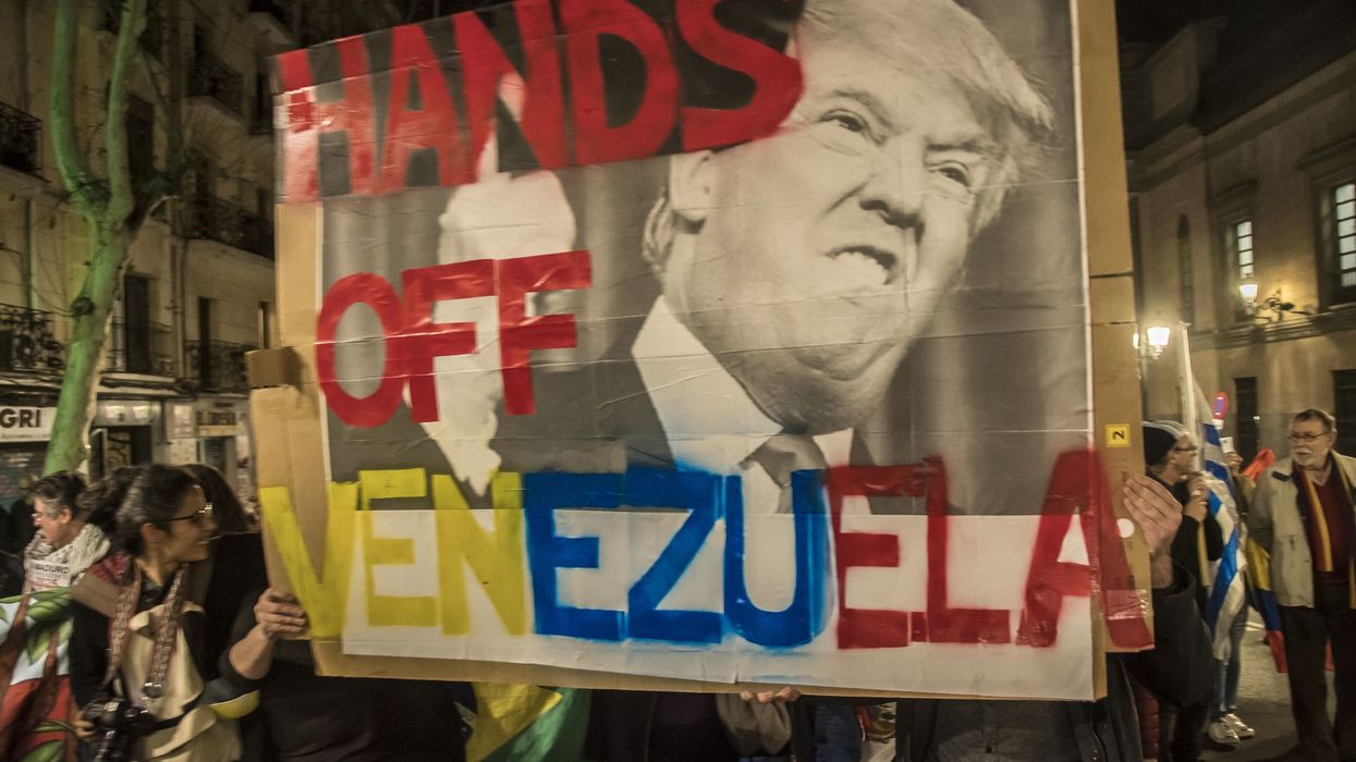 A protester seen holding a placard saying, "Hands off Venezuela" with an image of Trump.