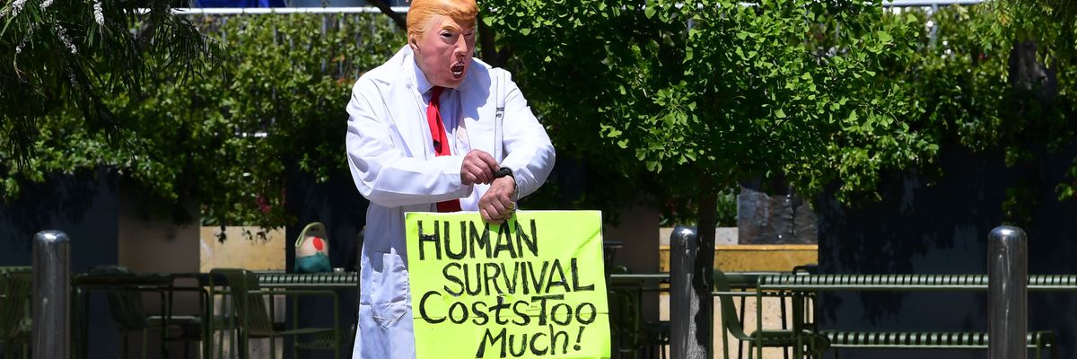 A protester wearing a Trump holds a sign that reads "Human survival costs too much"
