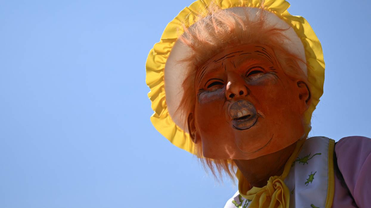 A protester wears a mask of Donald Trump in a bonnet.