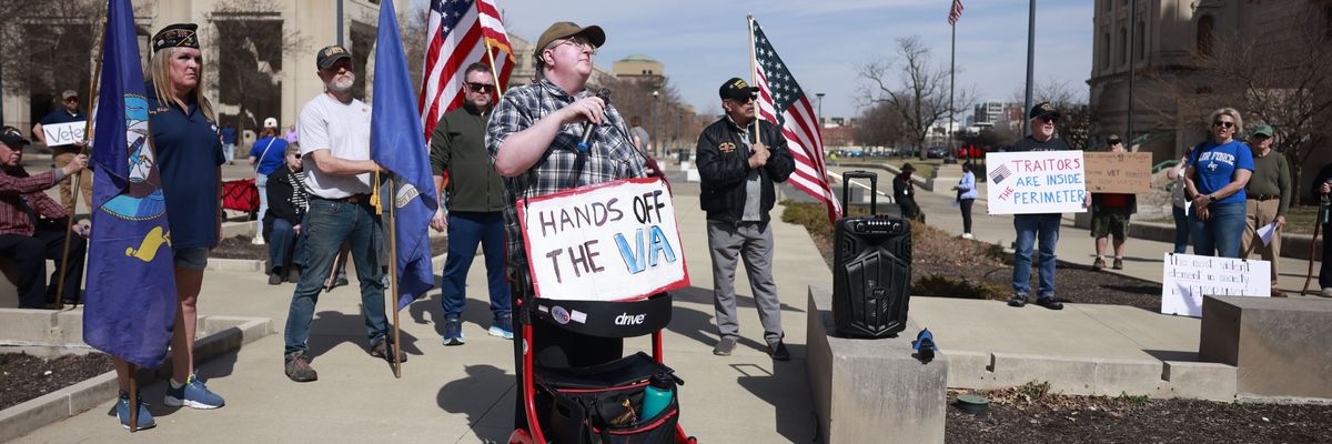 A protester wears a sign reading, "Hands off the VA" at a protest in Indianapolis, Indiana