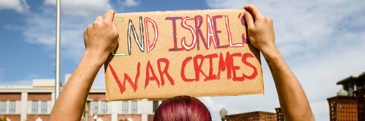 A protestor holds a placard saying End Israels war crimes