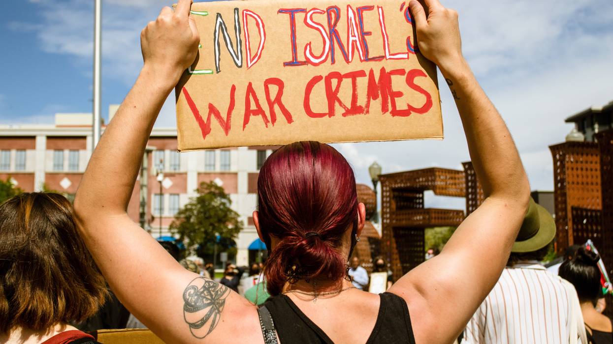 A protestor holds a placard saying End Israels war crimes