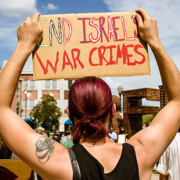 A protestor holds a placard saying End Israels war crimes