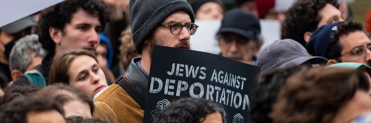 A protestor holds a sign that says "Jews Against Deportation"