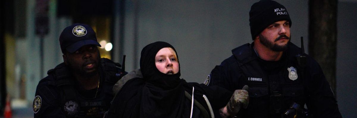 A protestor in black between two police.
