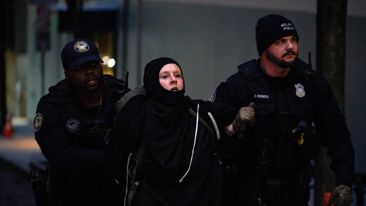 A protestor in black between two police.