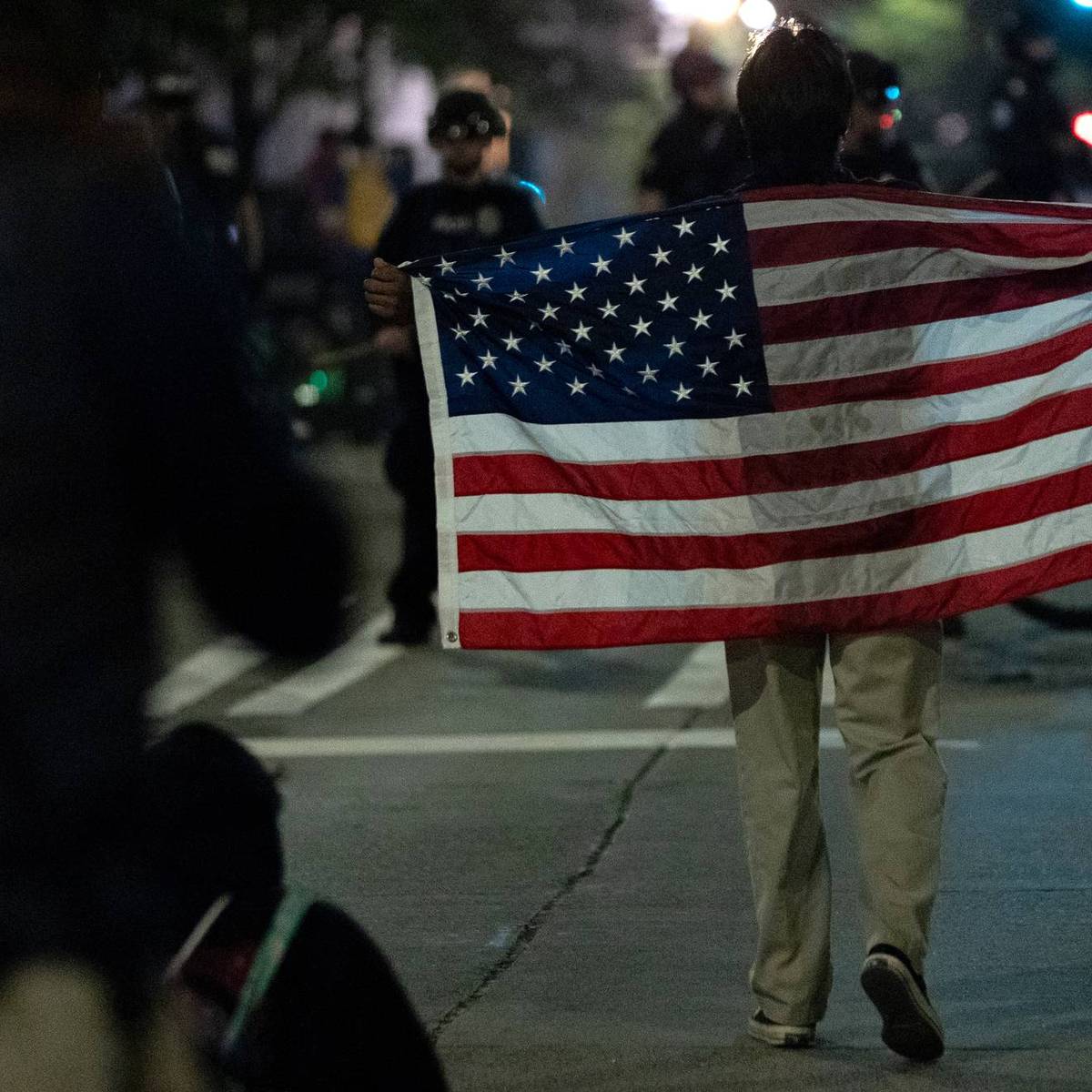 A protestor with an American flag walks
