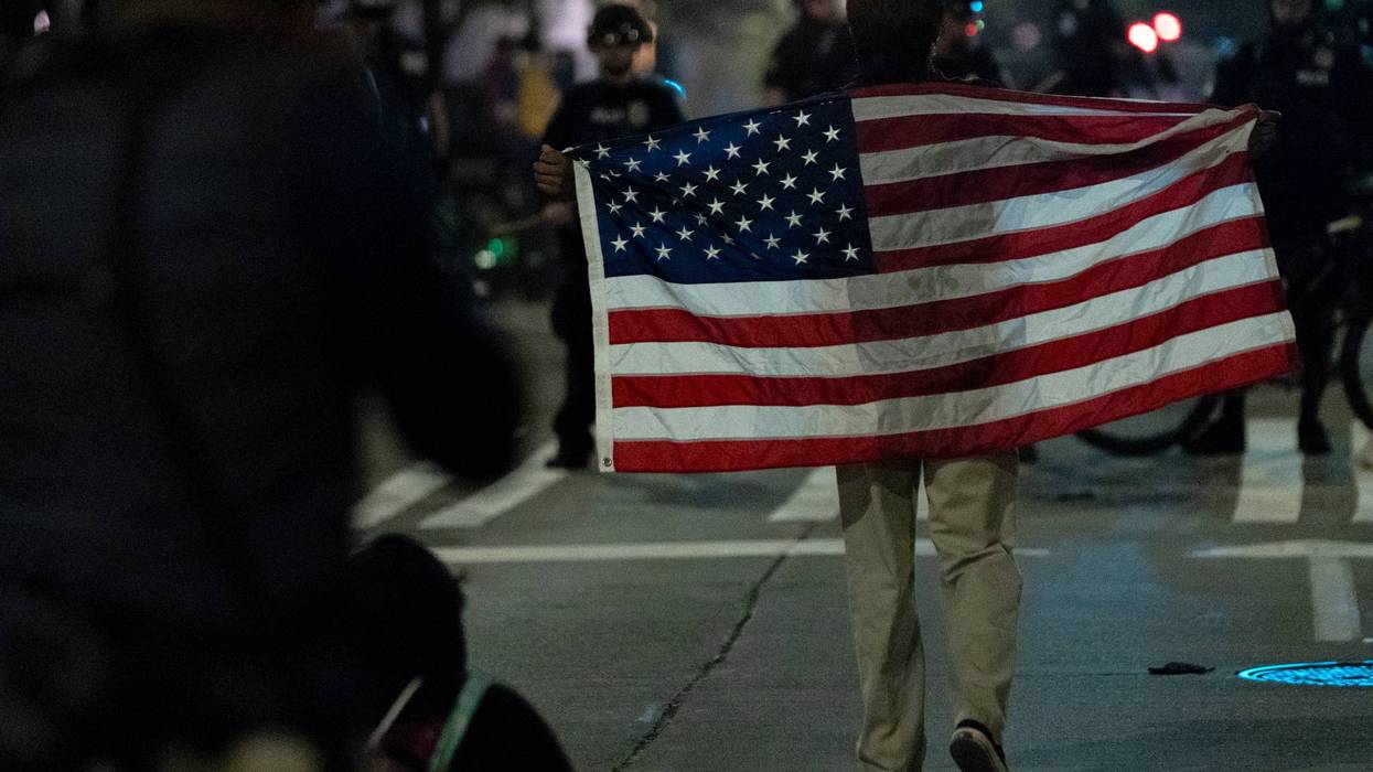 A protestor with an American flag walks