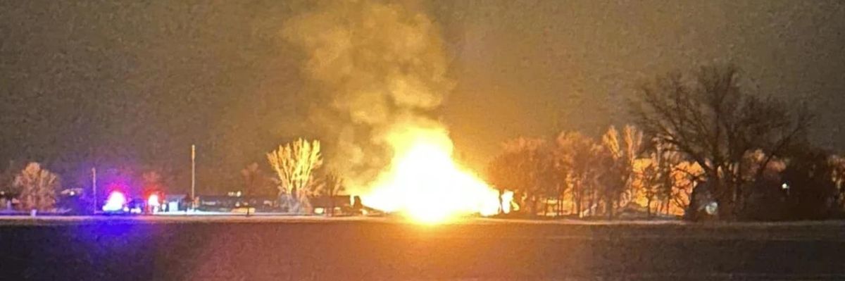 A Raymond, Minnesota resident takes a photo of the fiery BNSF train derailment