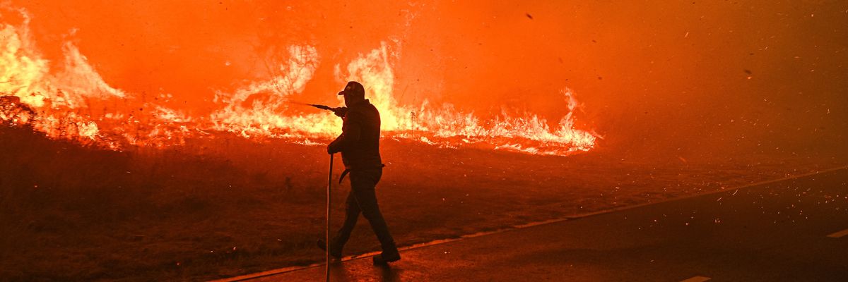 A resident tries to fight a wildfire burning