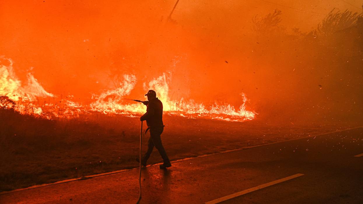 A resident tries to fight a wildfire burning
