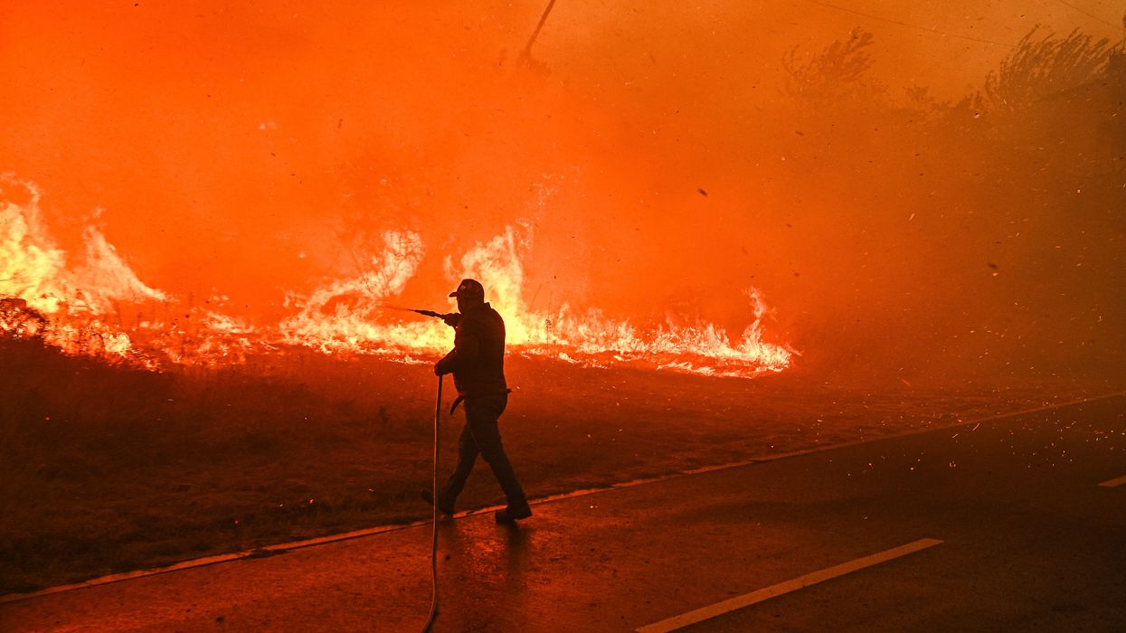 A resident tries to fight a wildfire burning