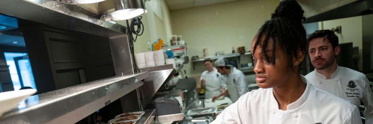 A restaurant worker finishes a breakfast dish