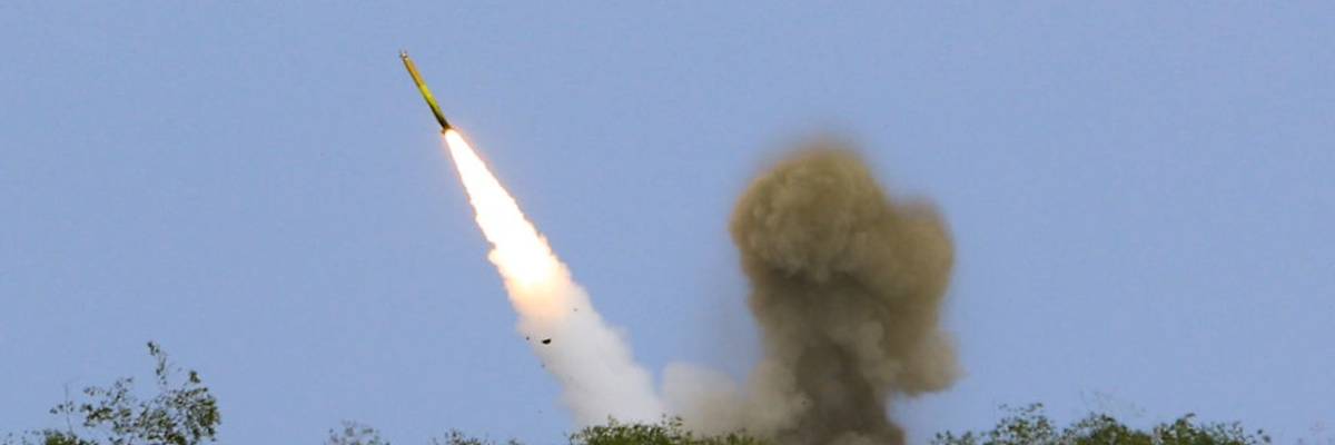 A rocket launches above trees.