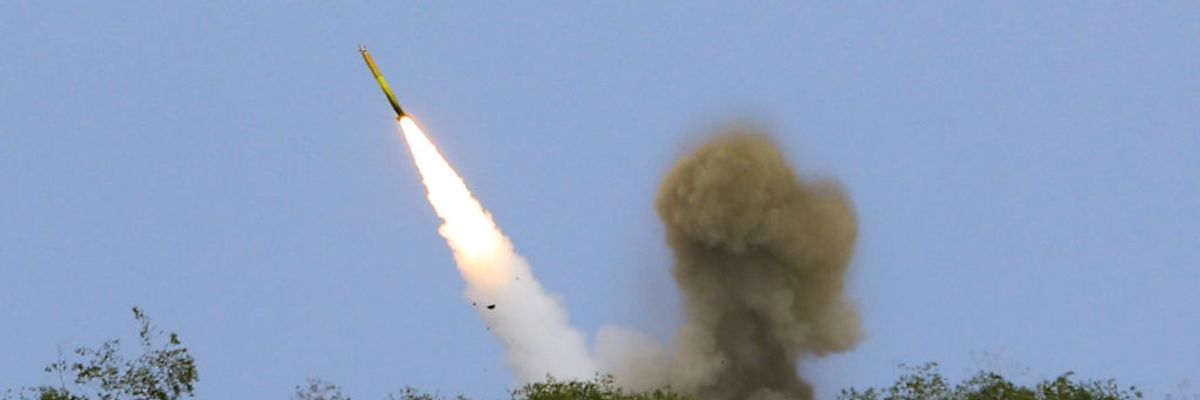 A rocket launches above trees.