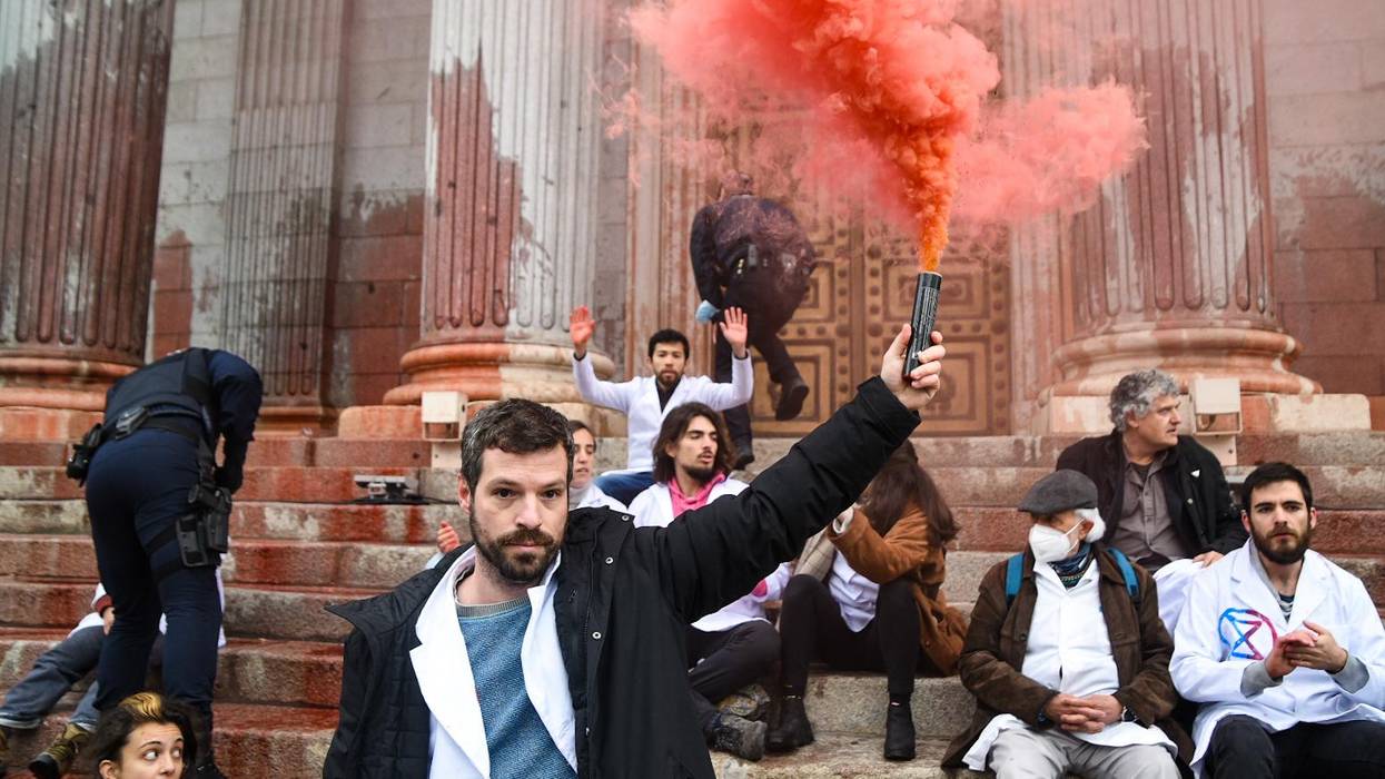 A scientist lifts a red smoke bomb into the air.