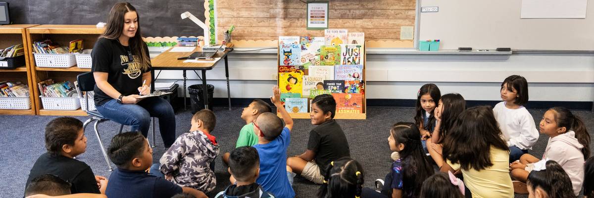 A second grade teacher greets students