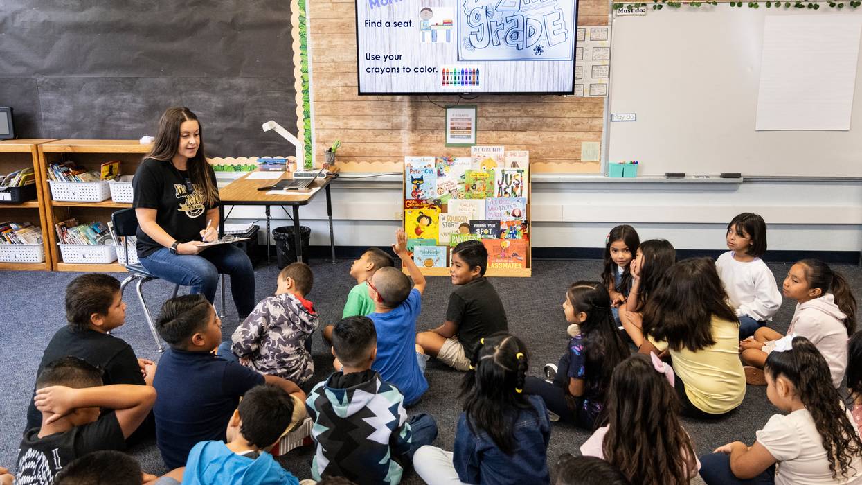 A second grade teacher greets students