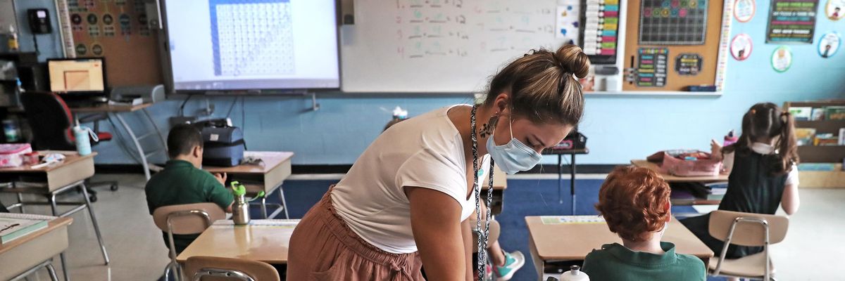 A second grade teacher sanitizes students' desks for snack time at South Boston Catholic Academy in South Boston on Sept. 10, 2020.