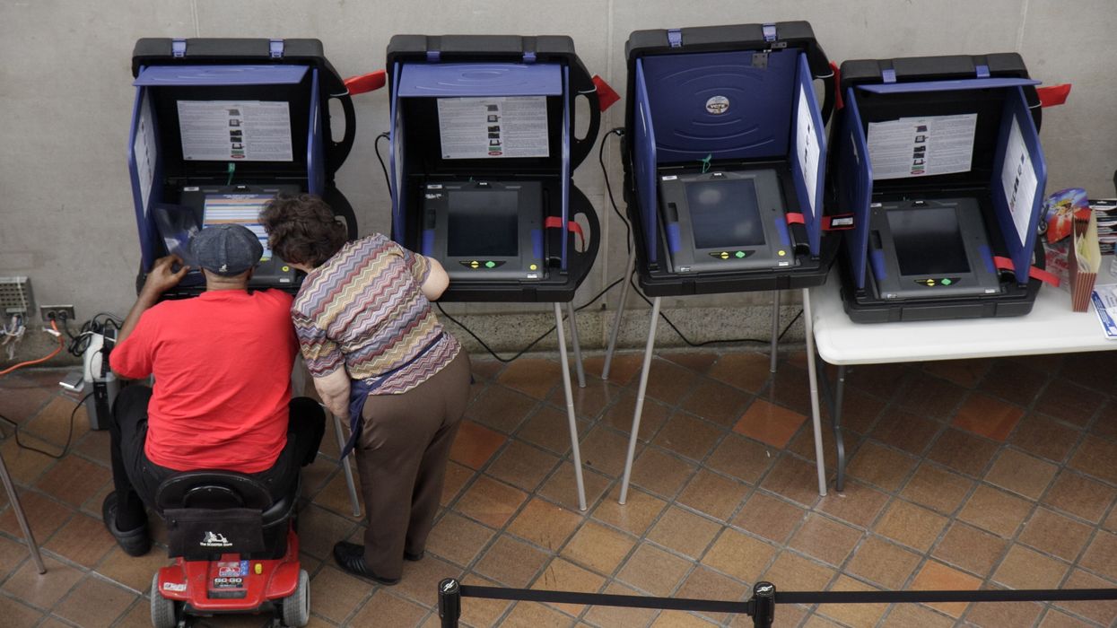 A senior woman assisting a man in an electric scooter at the voting machines for early voting at the Stephen P. Clark Government Center.