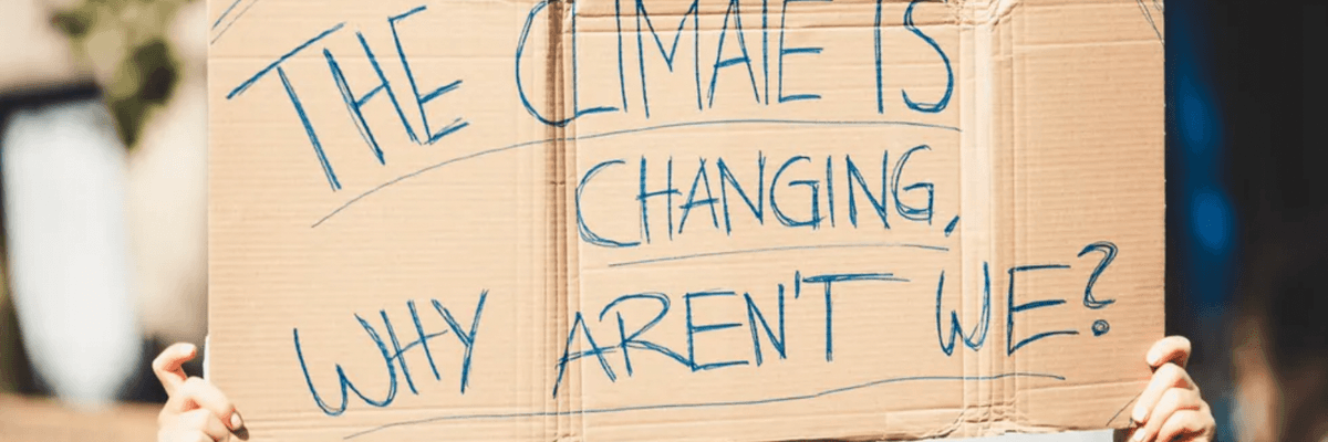 A sign at a protest reads, "The climate is changing, why aren't we?"