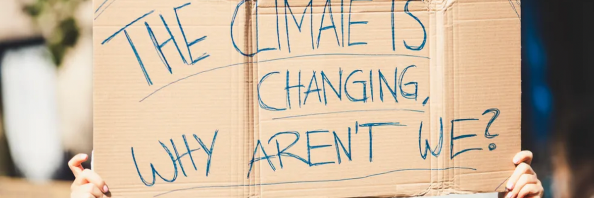 A sign at a protest reads, "The climate is changing, why aren't we?"