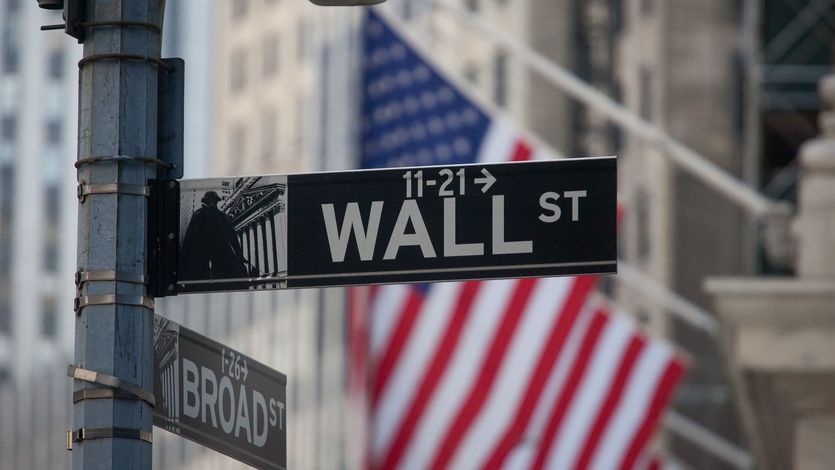 A sign for Wall Street and American flags in New York, U.S..