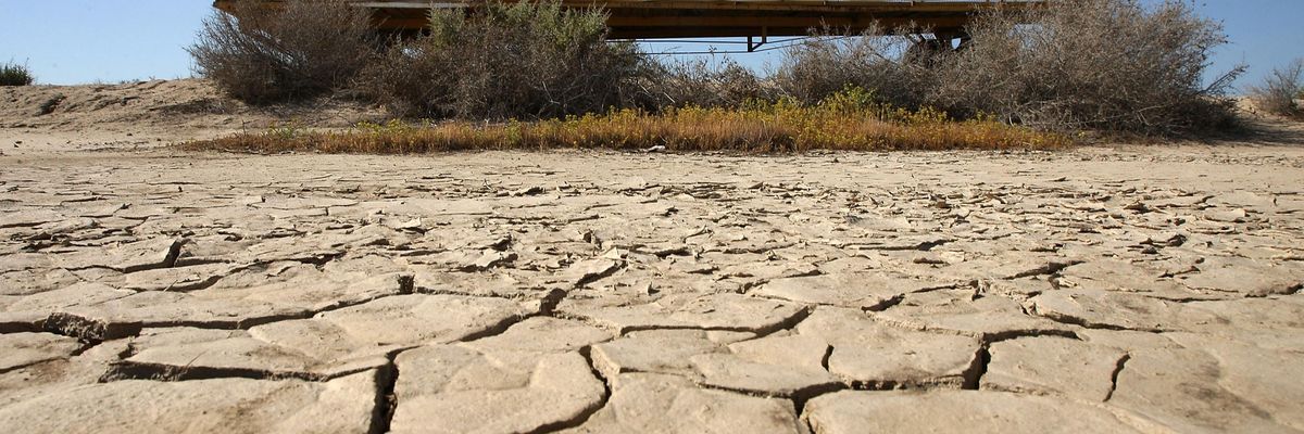 A sign on a farm trailer reading "Food grows where water flows" hangs over dry, cracked mud at the edge of a farm on April 16, 2009 near Buttonwillow, California.