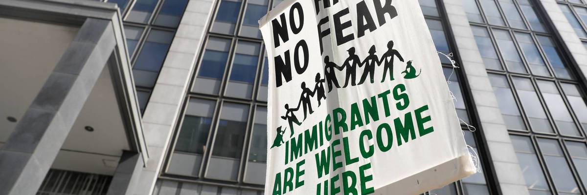 A sign reading, "No Hate No Fear Immigrants Welcome Here" held outside the Phillip Burton Federal Building.
