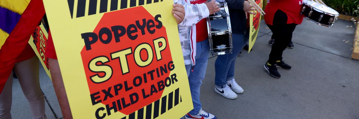 A sign reading "Popeyes Stop Exploiting Child Labor" held at a rally.