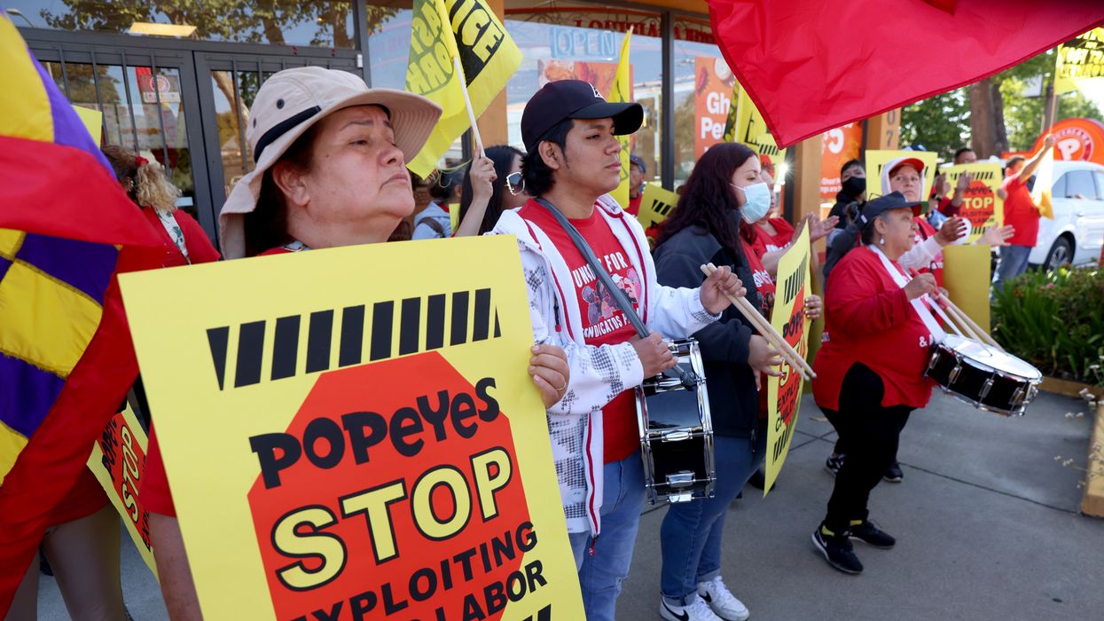A sign reading "Popeyes Stop Exploiting Child Labor" held at a rally.