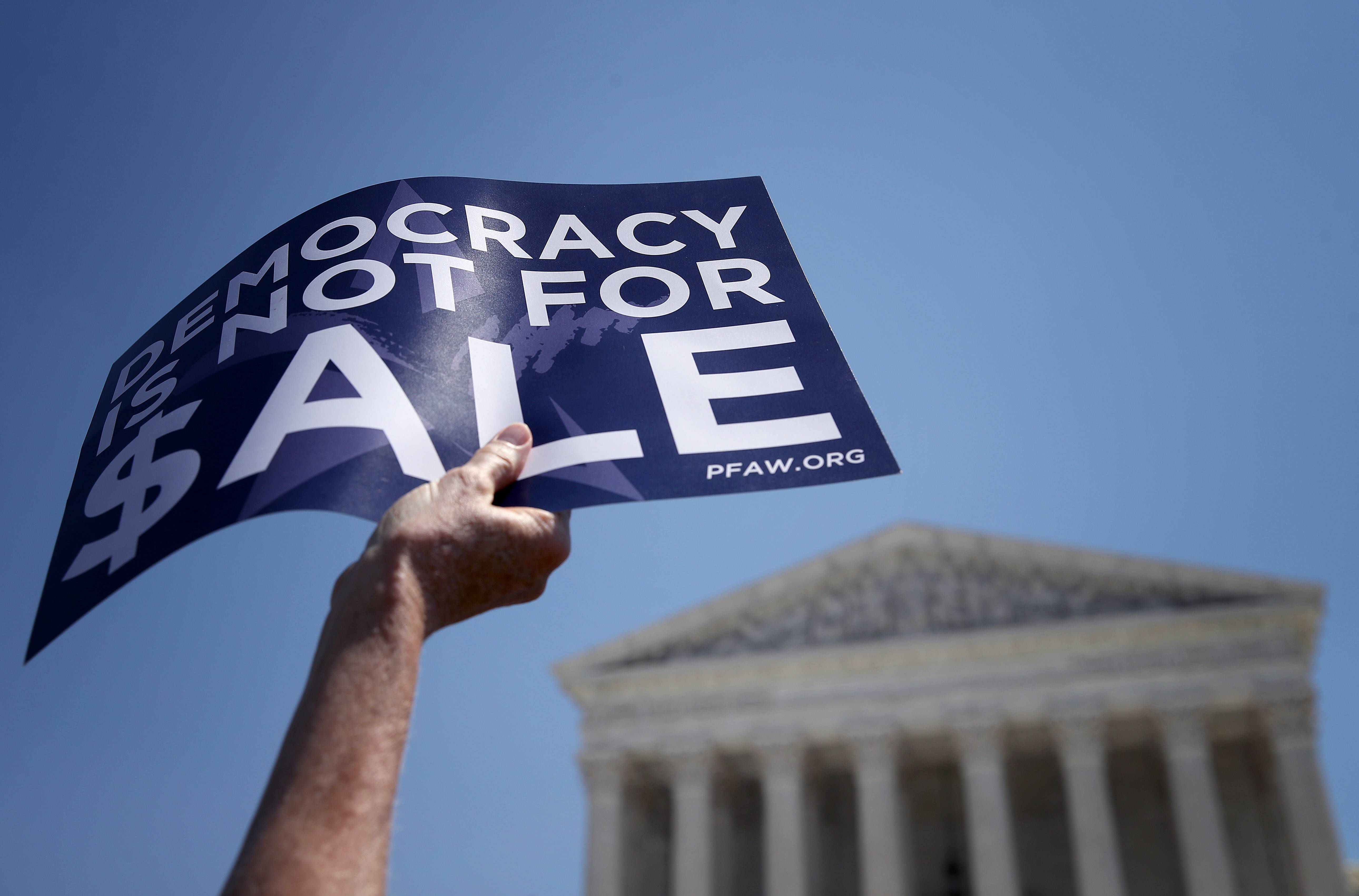A sign reads "democracy is not for sale"