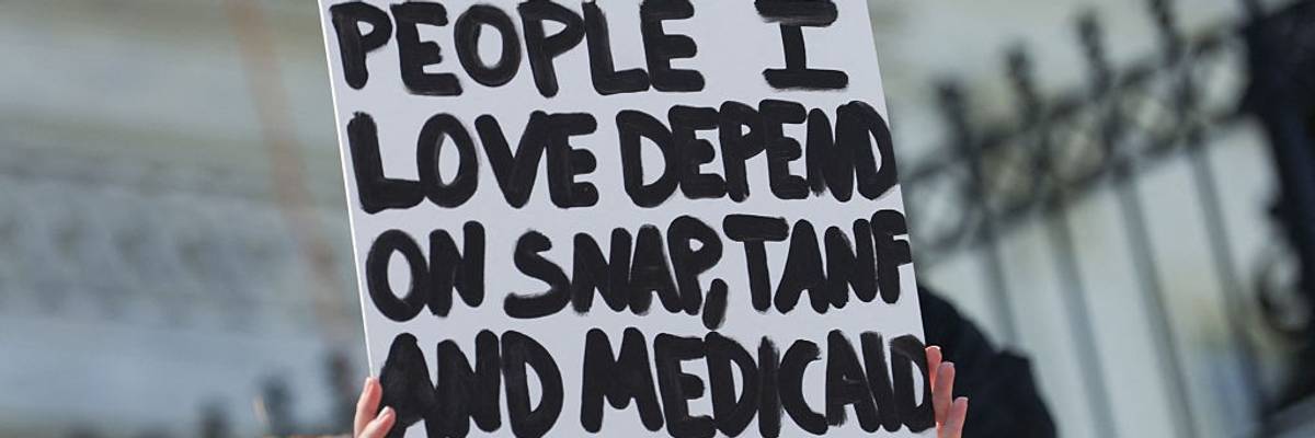 A sign reads, "People I love depend on SNAP, TANF, and Medicaid"