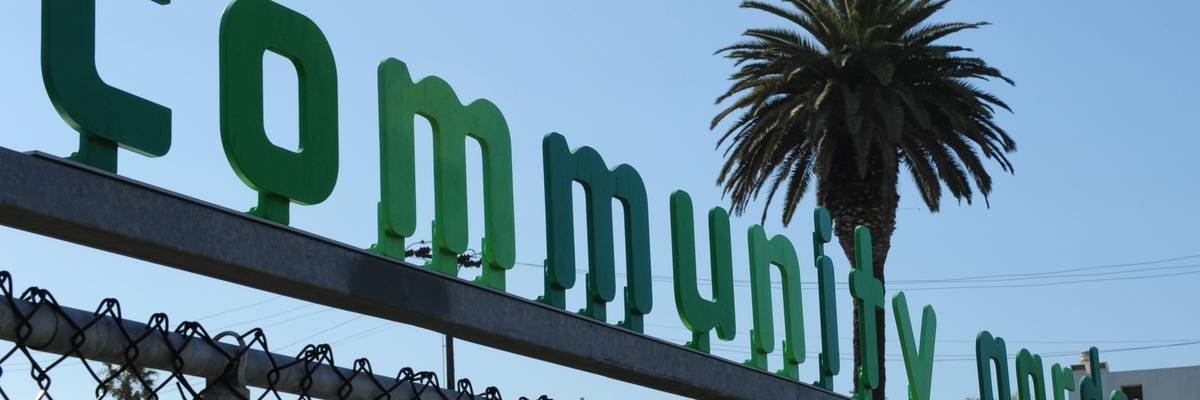 A sign saying Community Garden over a chain-link fence.