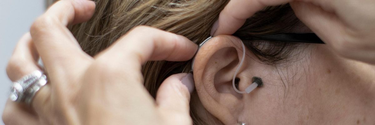 A specialist places a hearing aid on a patient