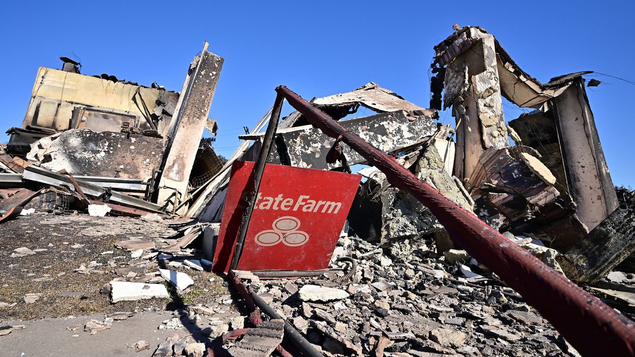 A State Farm insurance company sign sits amid the rubble of a building destroyed by the Palisades Fire