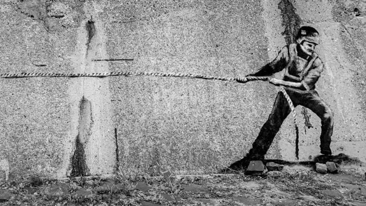 A street art mural depicting a tug-of-war between a Russian and Ukrainian soldier is seen on a war memorial in Izyum