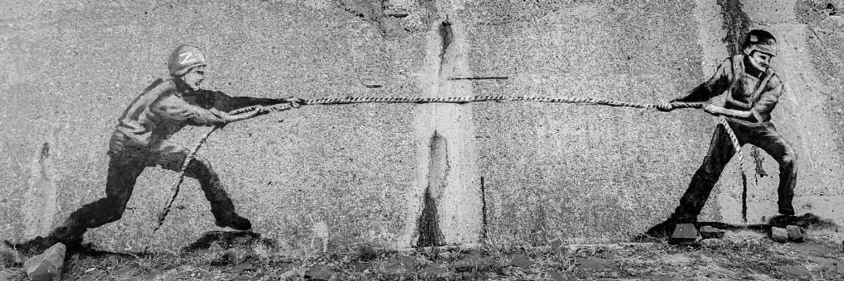 A street art mural depicting a tug-of-war between a Russian and Ukrainian soldier.