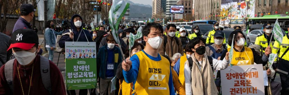 A street in Seoul, South Korea, filled with people marching with signs.