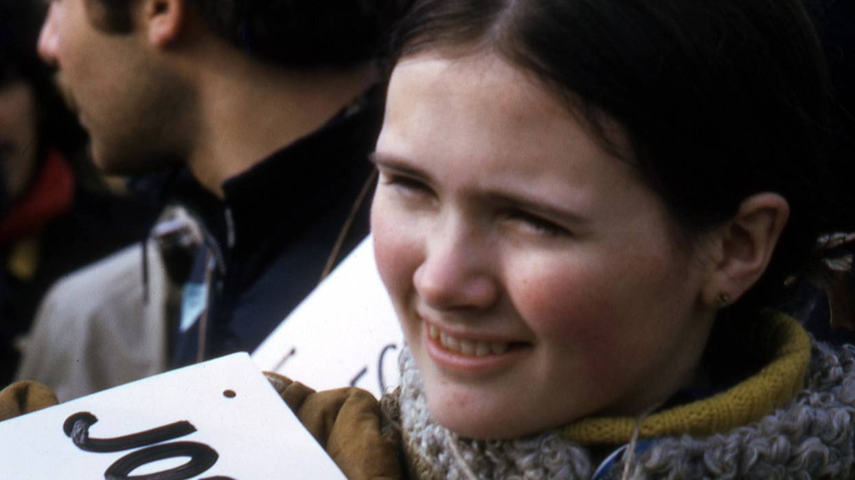 A student holds a sign with the name of a soldier killed during the Vietnam War.