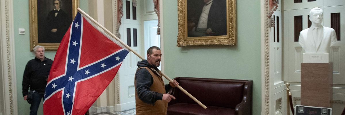 A supporter of US President Donald Trump carries a Confederate flag as he protests in the US Capitol Rotunda on January 6, 2021, in Washington, DC.