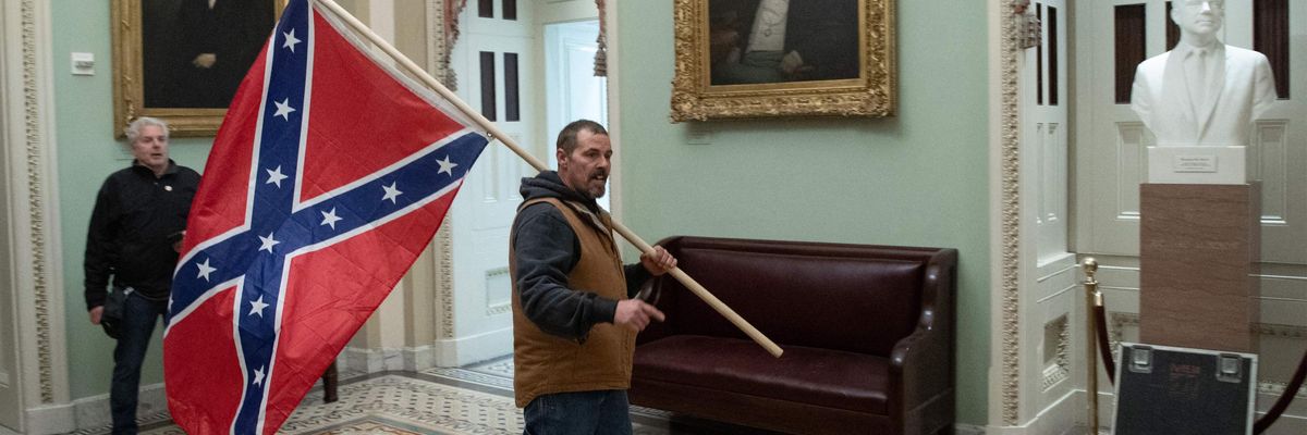 A supporter of US President Donald Trump carries a Confederate flag as he protests in the US Capitol Rotunda on January 6, 2021, in Washington, DC.