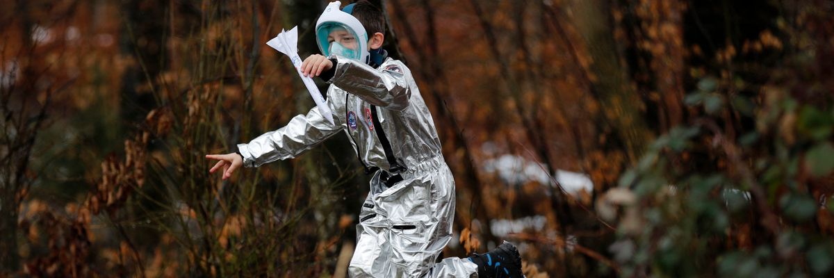 A Swiss student in spacesuit costume flies a paper rocket during a Mission to Mars science project