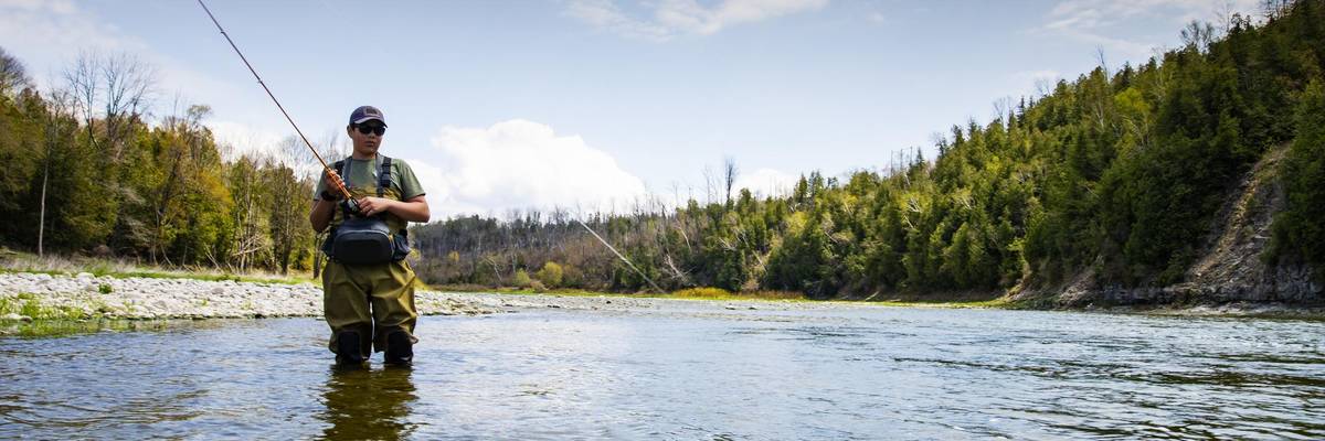 A teen fishes in a tributary river