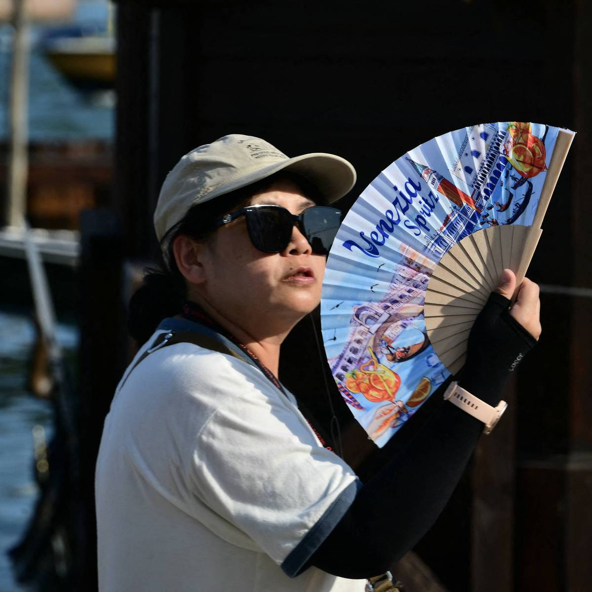 A tourist uses a hand fan to cool herself