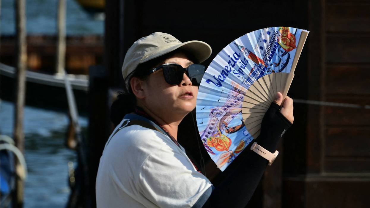 A tourist uses a hand fan to cool herself