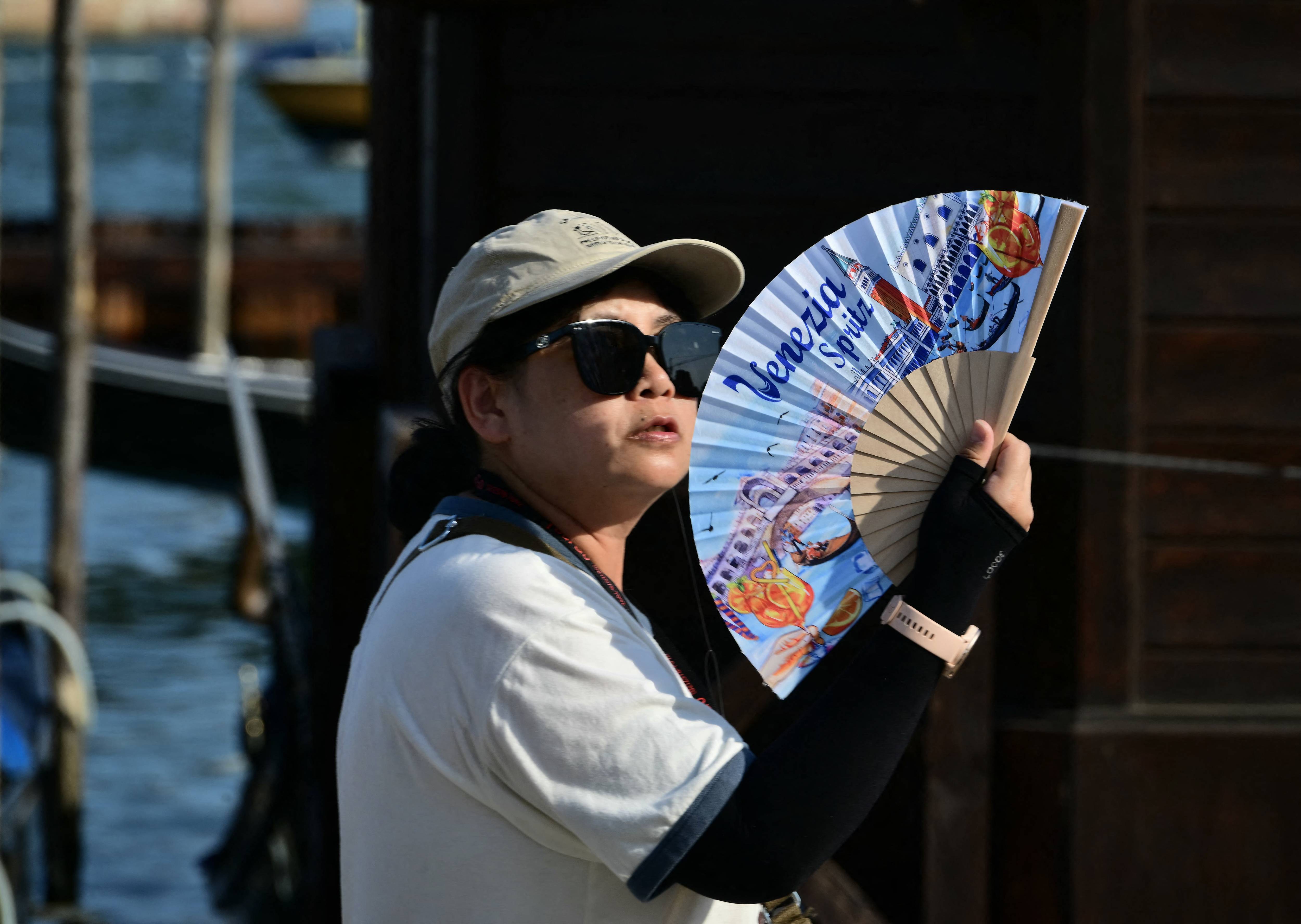 A tourist uses a hand fan to cool herself